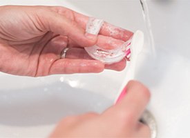 A person cleaning their Invisalign aligners