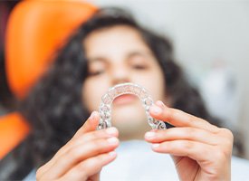 A teenager holding up an Invisalign aligner