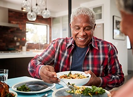 a man serving food to his family at the dinner table