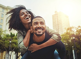 a smiling woman getting a piggy back ride from a man