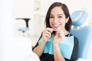 an adult putting clear aligners in their mouth at the dentist's office