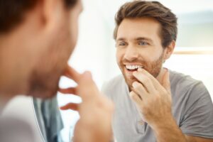 a man looking at his teeth in a mirror